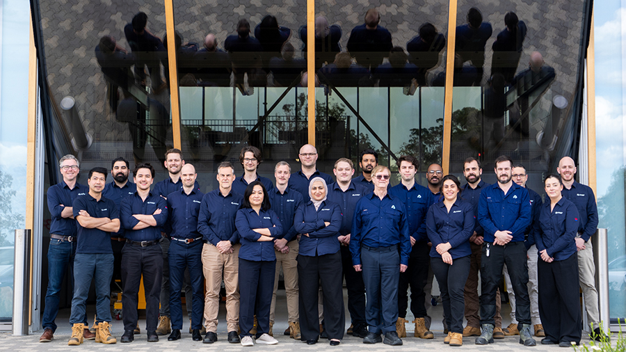 The AMRF team members lined up in front of a glass wall at First Building