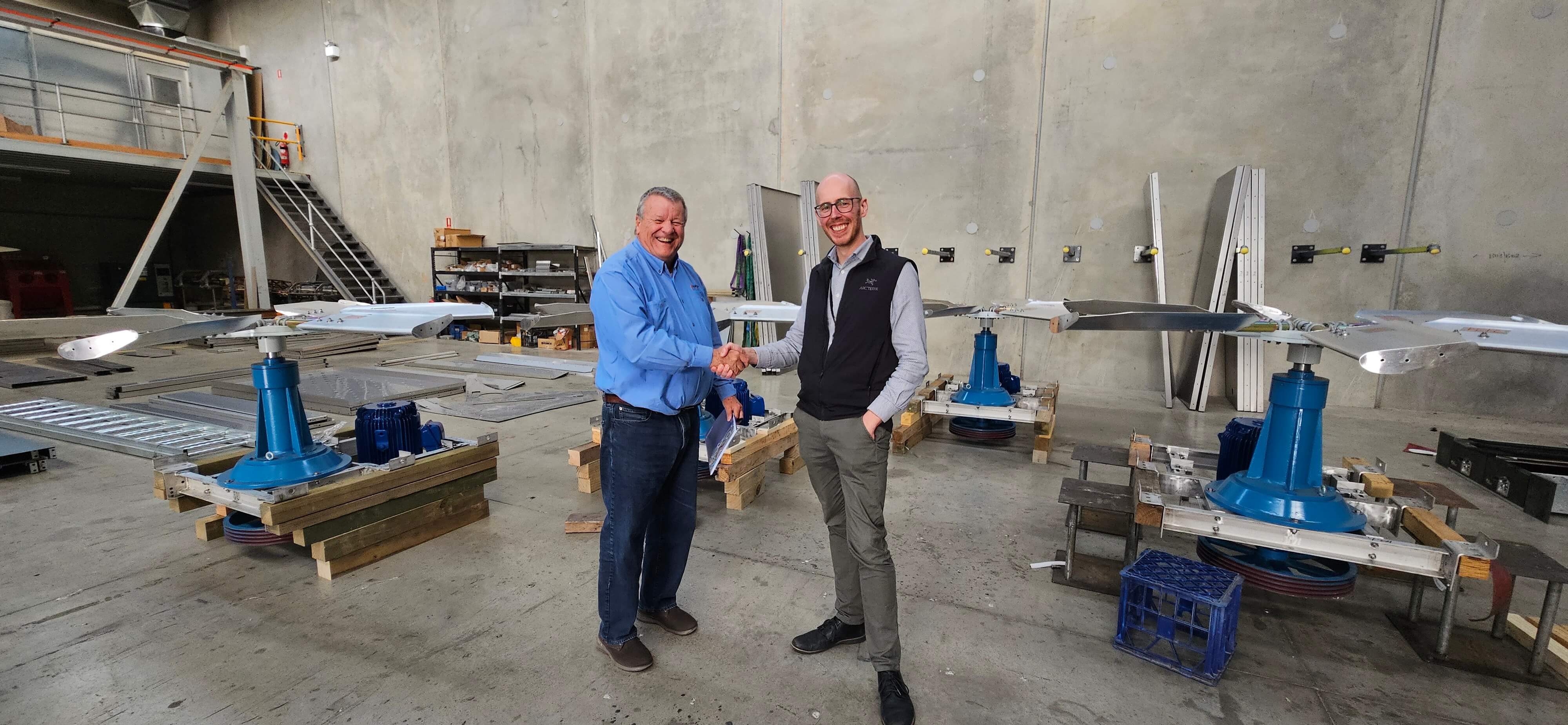 Two men wearing shaking hands in a factory